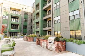 A courtyard with a brick wall and a grill surrounded by apartment buildings.